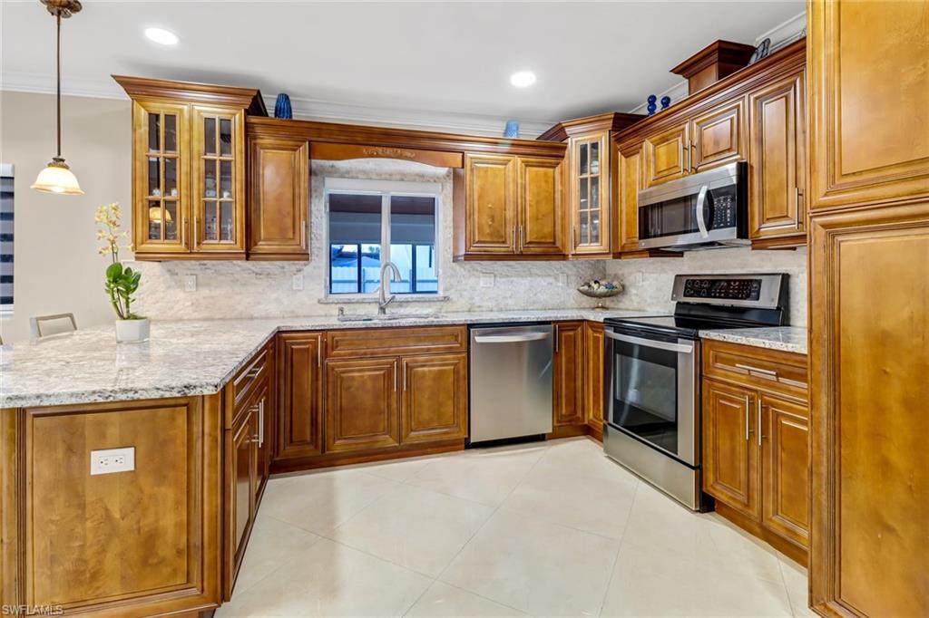 2001 43rd Terrace Southwest Naples, FL 34116 - Photo 11 of 27 a kitchen with stainless steel appliances granite countertop a sink stove and refrigerator