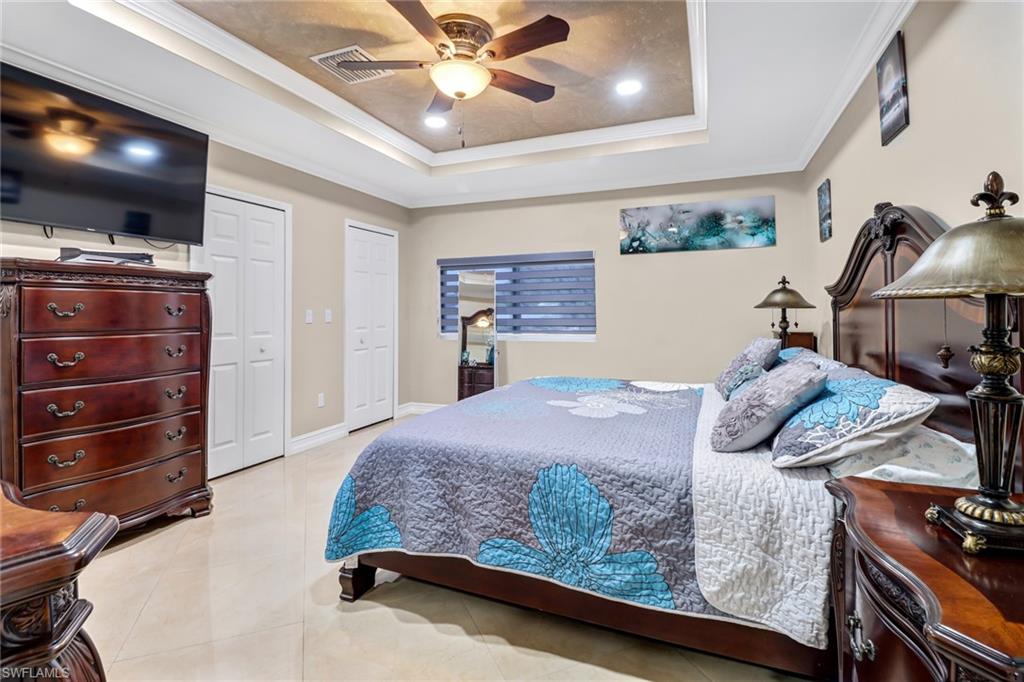 2001 43rd Terrace Southwest Naples, FL 34116 - Photo 13 of 27 a bedroom with a bed and a flat tv screen on dresser