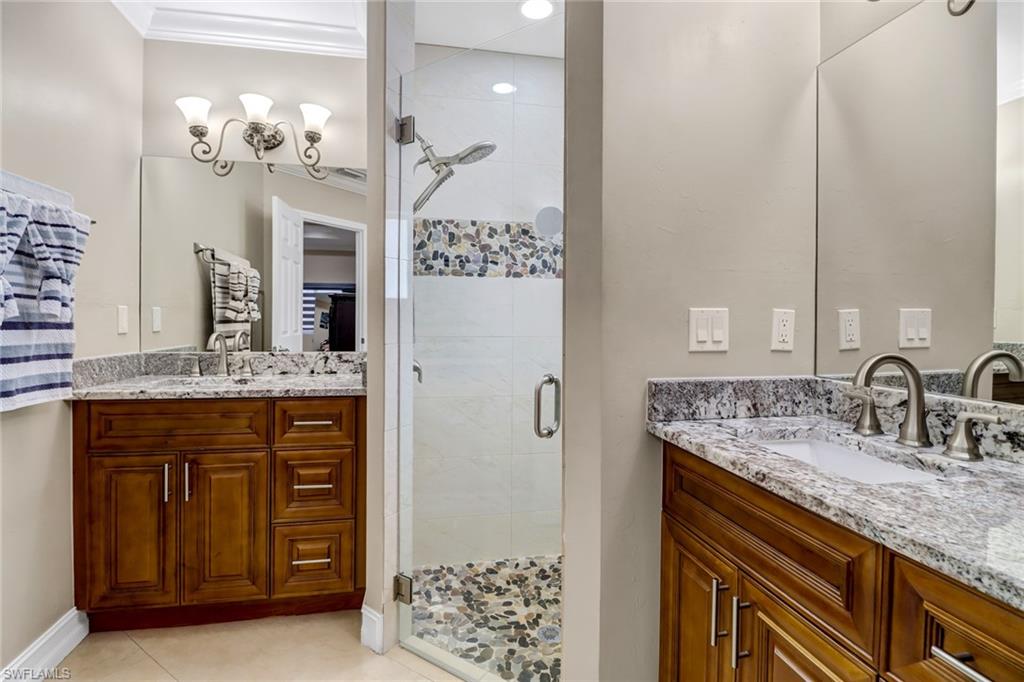 2001 43rd Terrace Southwest Naples, FL 34116 - Photo 16 of 27 a bathroom with a granite countertop sink a large mirror and a shower