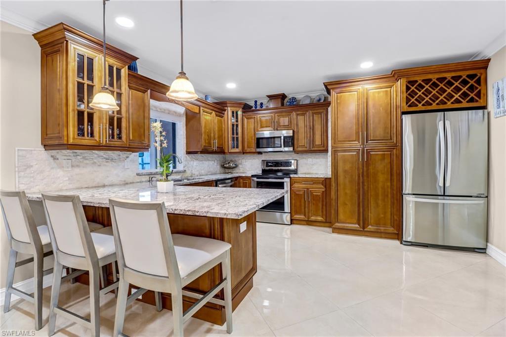 2001 43rd Terrace Southwest Naples, FL 34116 - Photo 10 of 27 a kitchen with stainless steel appliances granite countertop a refrigerator a stove a sink a dining table and chairs with wooden floor