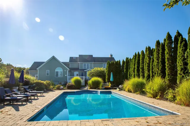 a view of a swimming pool with a chairs and floor to ceiling window