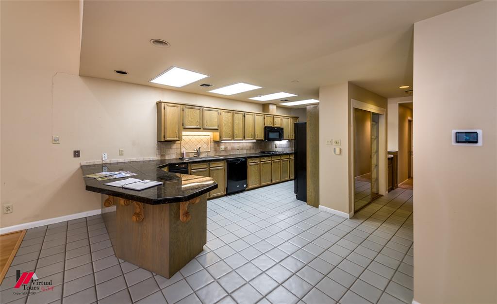 300 Pierremont Road, Unit 40 Shreveport, LA 71106 - Photo 11 of 34 Kitchen featuring wood-finish cabinetry, black appliances, dark stone countertops, and tile flooring