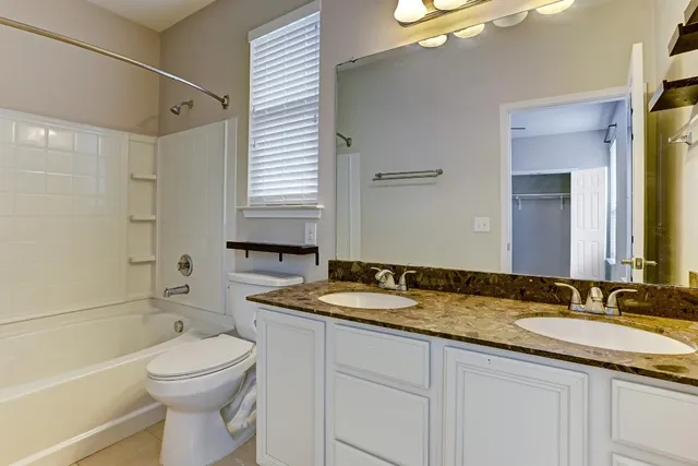 a bathroom with a granite countertop sink a toilet a mirror and shower