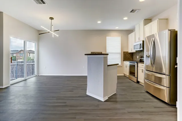 a kitchen with stainless steel appliances a refrigerator and wooden floor