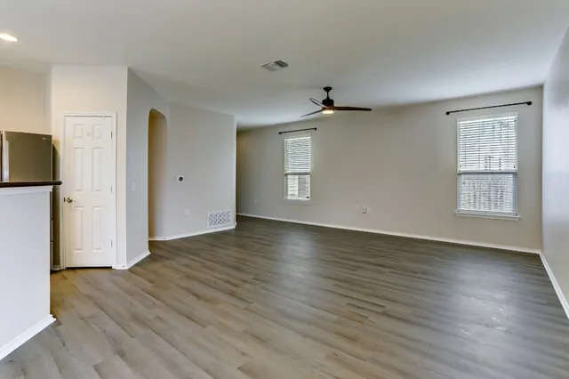 a view of an empty room with wooden floor and a window