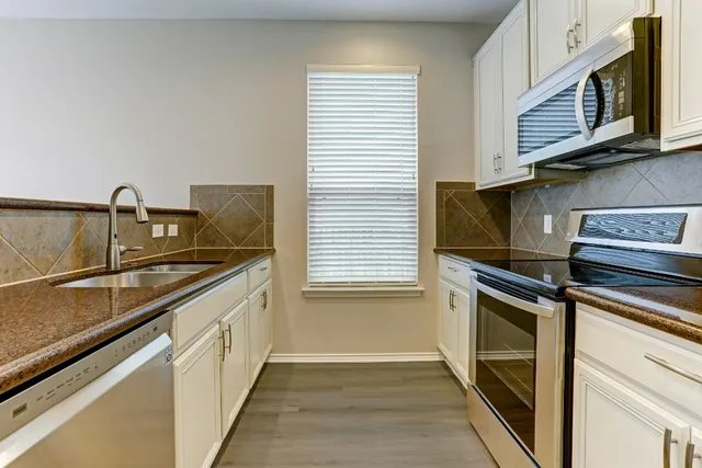a kitchen with stainless steel appliances granite countertop a sink stove and microwave