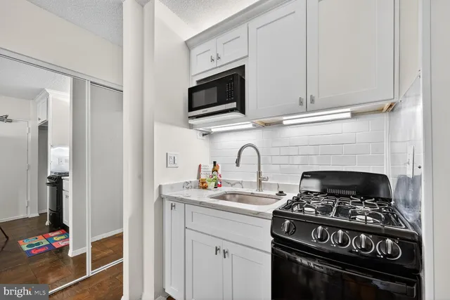 a kitchen with stainless steel appliances granite countertop white cabinets a stove top oven and cabinetry