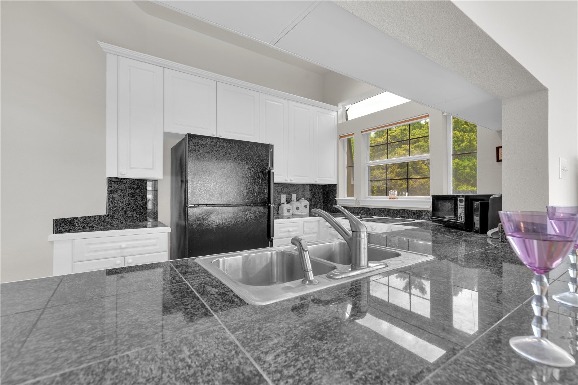 2918 Ranch Road 620 North, Unit L173 Austin, TX 78734 - Photo 10 of 35 Kitchen featuring freestanding refrigerator, tile counters, a sink, and backsplash
