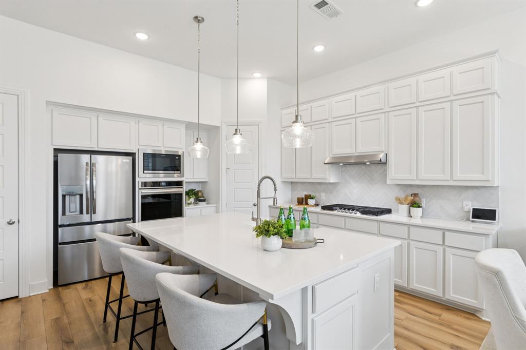 1903 Midhurst Drive Forney, TX 75126 - Photo 4 of 31 a kitchen with stainless steel appliances granite countertop a sink a stove a refrigerator cabinets and chairs