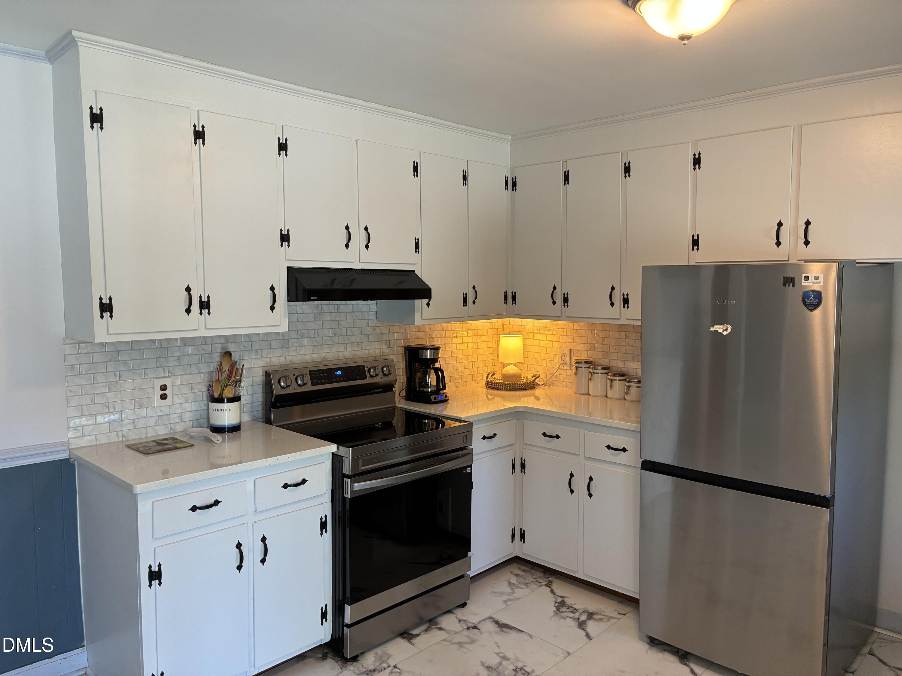 1727 Pinecrest Road Henderson, NC 27536 - Photo 5 of 14 a kitchen with a refrigerator stove and white cabinets