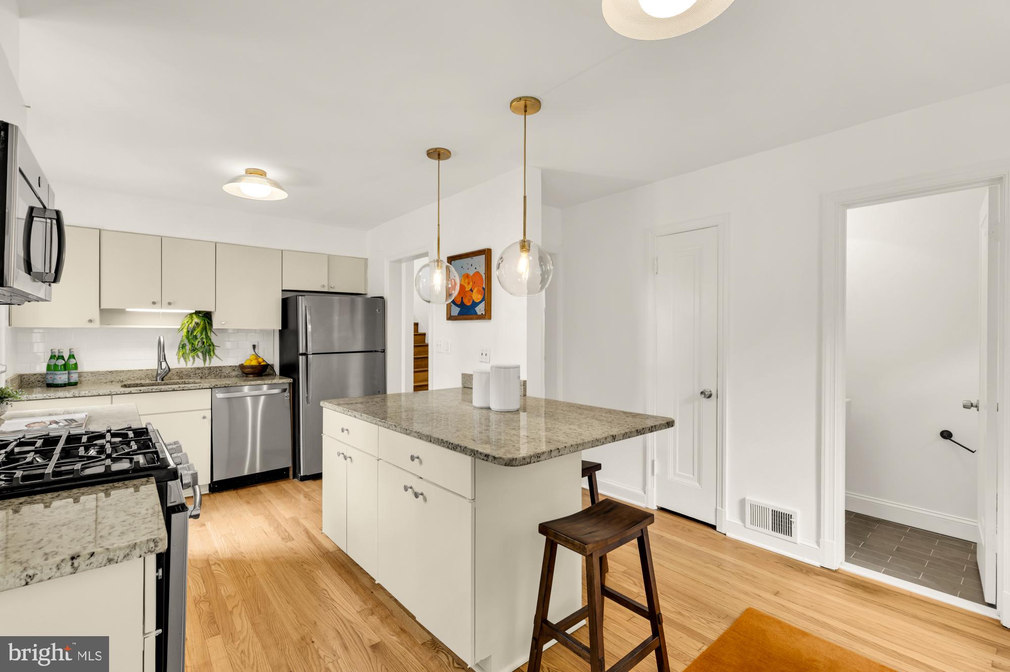 2030 Luzerne Avenue Silver Spring, MD 20910 - Photo 7 of 25 a kitchen with a sink a refrigerator a stove and white cabinets with wooden floor