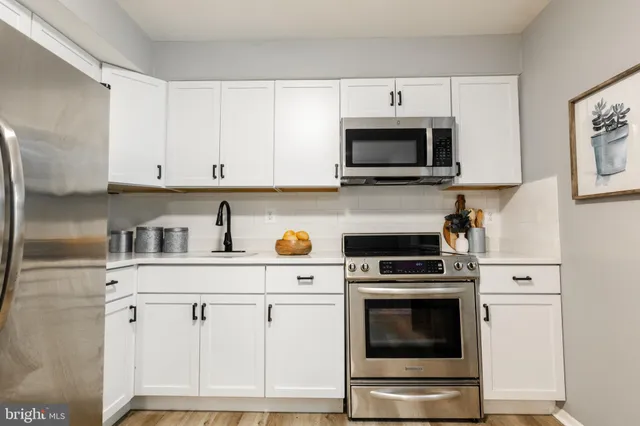 a kitchen with white cabinets and stainless steel appliances