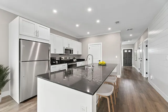 a kitchen with stainless steel appliances granite countertop a refrigerator a stove a microwave a sink a refrigerator white cabinets and wooden floor