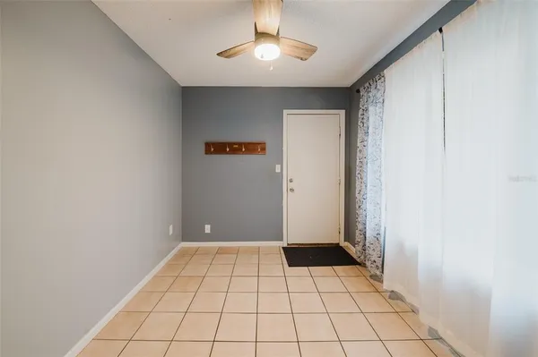 a view of an empty room with window and chandelier fan