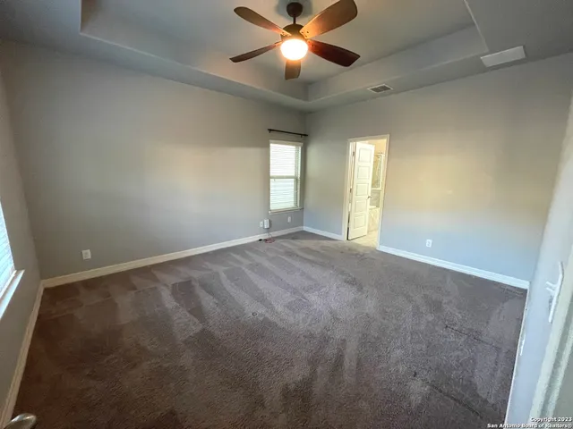 an empty room with windows and fan