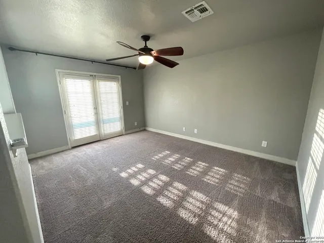 an empty room with windows and fan