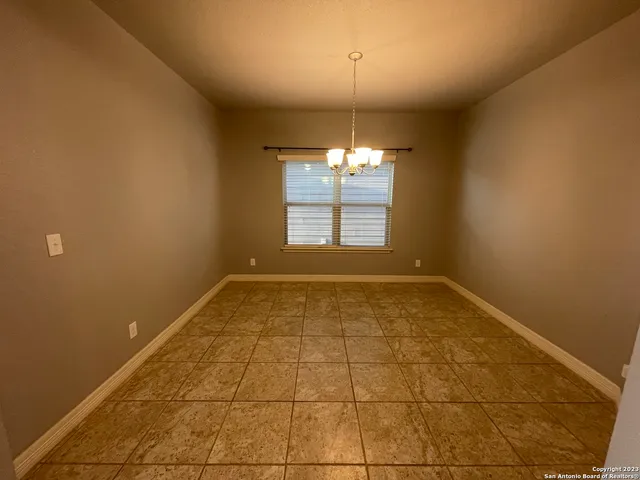 an empty room with chandelier fan and windows