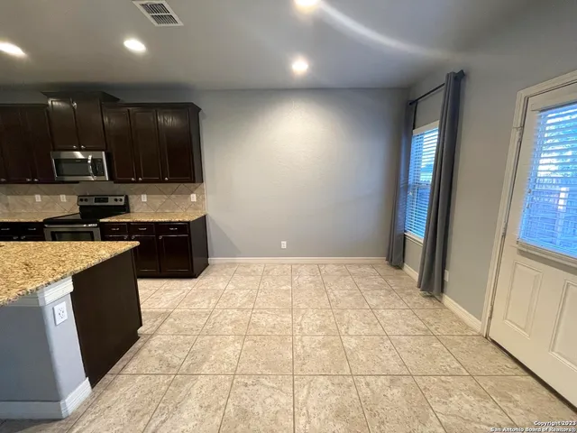 a large kitchen with kitchen island granite countertop a sink and a stove top oven