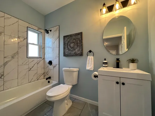 a bathroom with a toilet sink vanity tub and mirror
