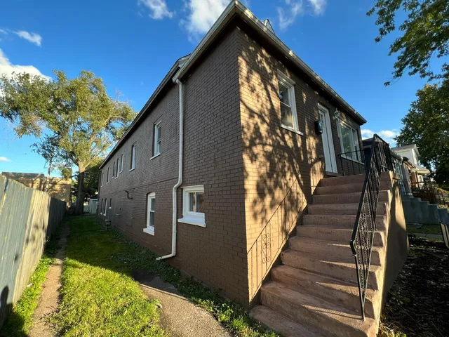 a brick house with a big yard and large trees