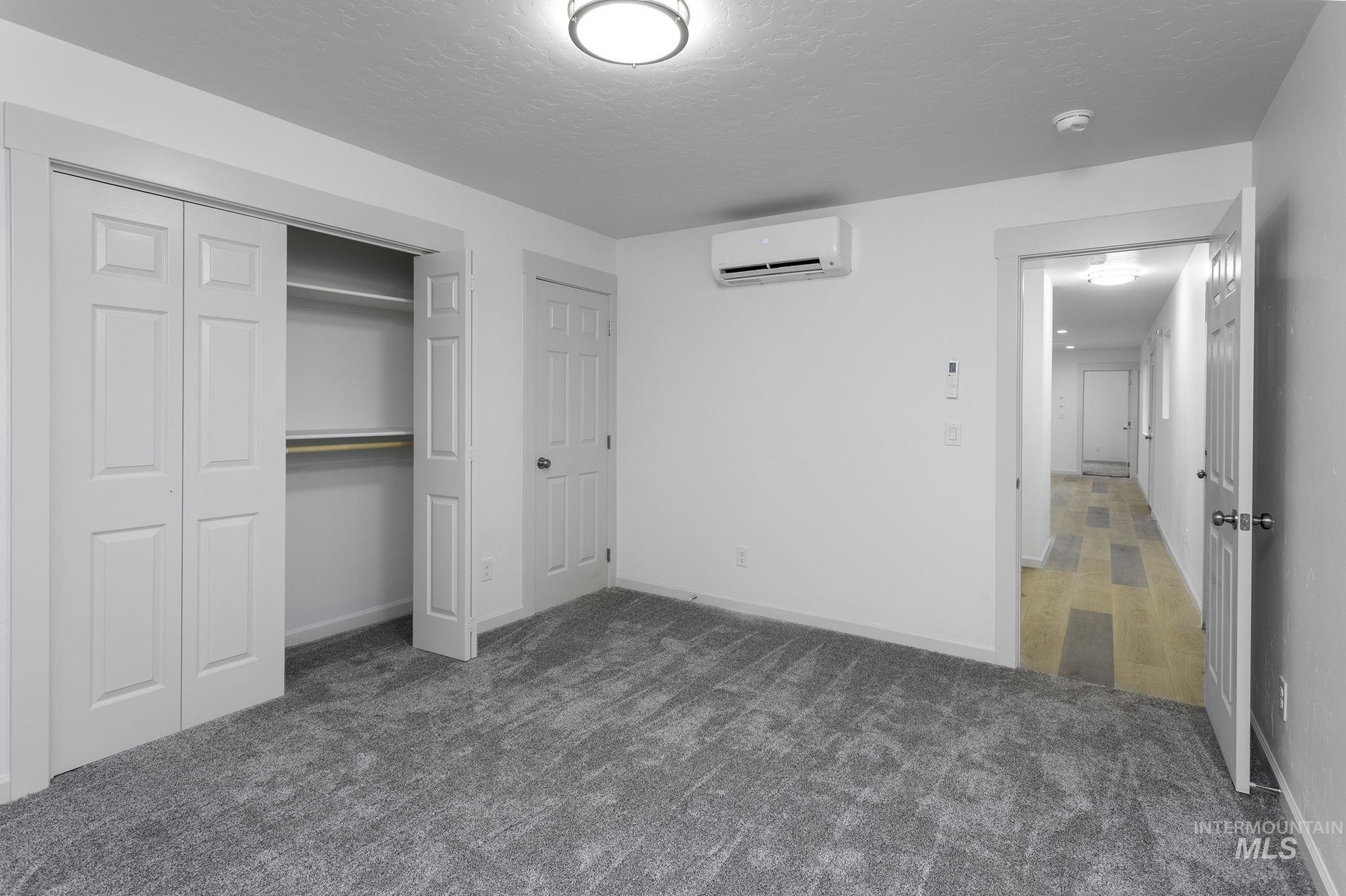 450 Greenleaf Street Boise, ID 83713 - Photo 17 of 17 Unfurnished bedroom with dark carpet, a closet, a textured ceiling, and a wall mounted AC