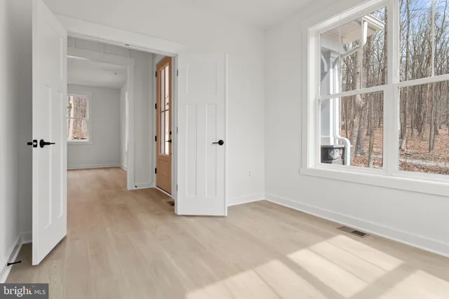 a view of an empty room with wooden floor and stairs