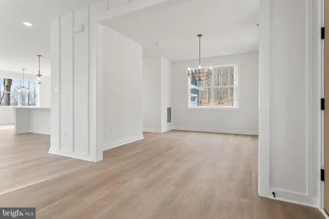 an empty room with wooden floor fireplace and windows