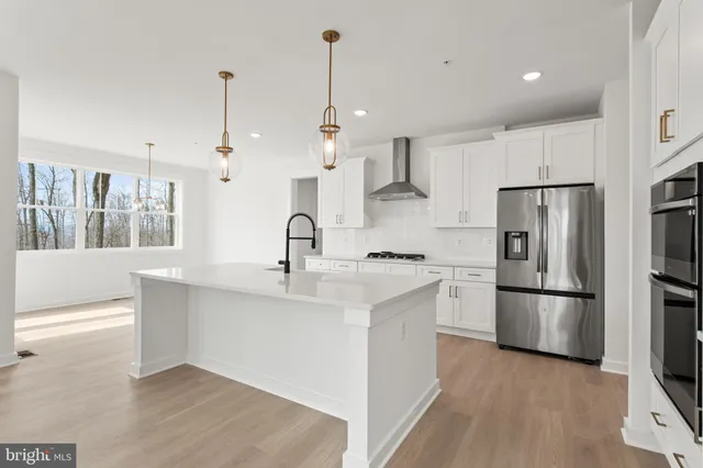 a kitchen with stainless steel appliances granite countertop a refrigerator a sink dishwasher a oven and white cabinets with wooden floor