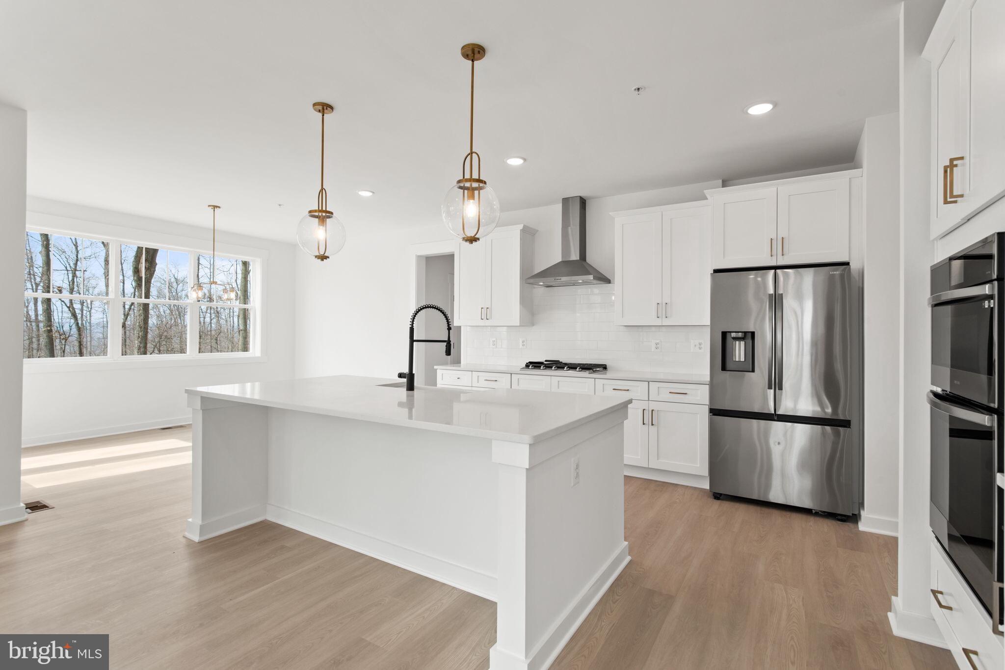6512 Shady Side Road Shady Side, MD 20764 - Photo 2 of 29 a kitchen with stainless steel appliances granite countertop a refrigerator a sink dishwasher a oven and white cabinets with wooden floor