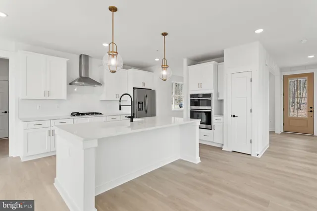 a large kitchen with kitchen island a sink a stove a refrigerator and white cabinets