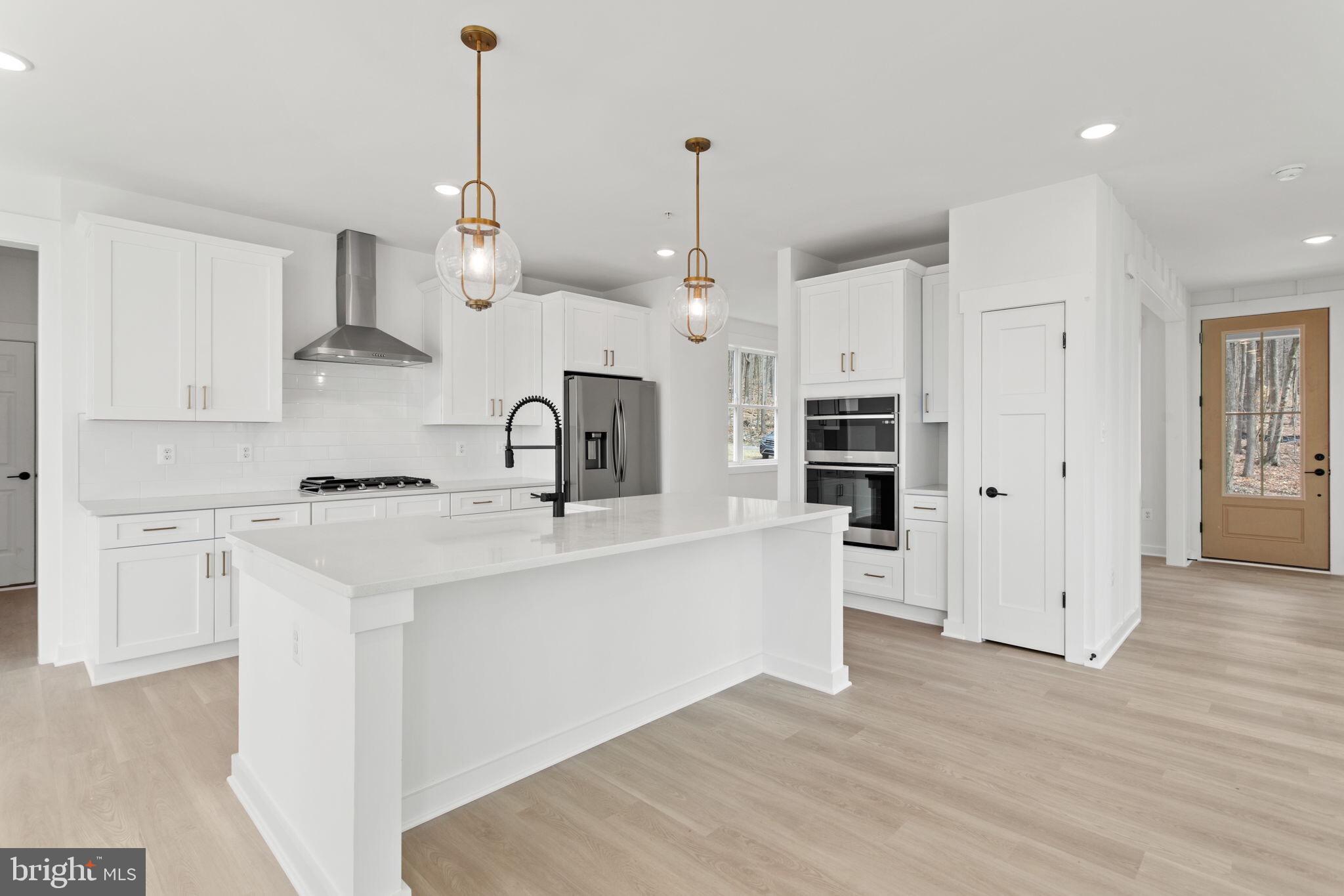 6512 Shady Side Road Shady Side, MD 20764 - Photo 3 of 29 a large kitchen with kitchen island a sink a stove a refrigerator and white cabinets