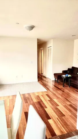 a view of a hallway with wooden floor and closet