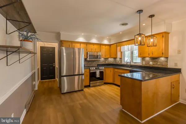 a kitchen with stainless steel appliances granite countertop a refrigerator a stove and a sink