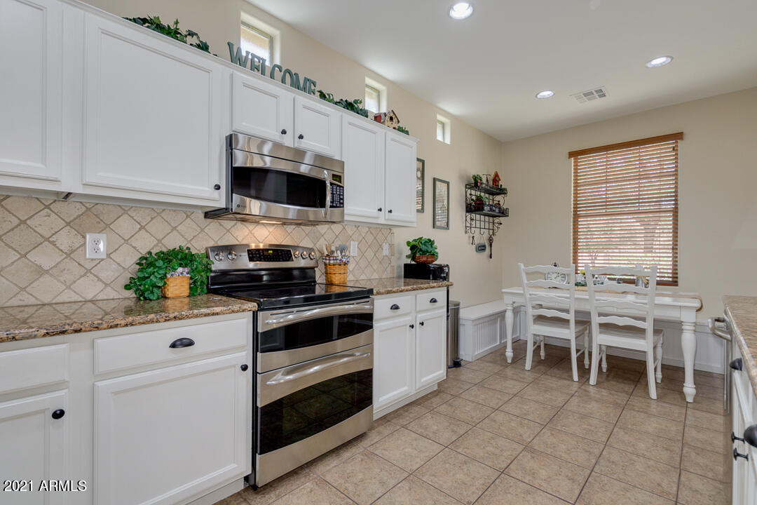 3763 East Larson Lane Gilbert, AZ 85295 - Photo 19 of 40 a kitchen with stainless steel appliances granite countertop a stove a sink dishwasher and white cabinets with wooden floor