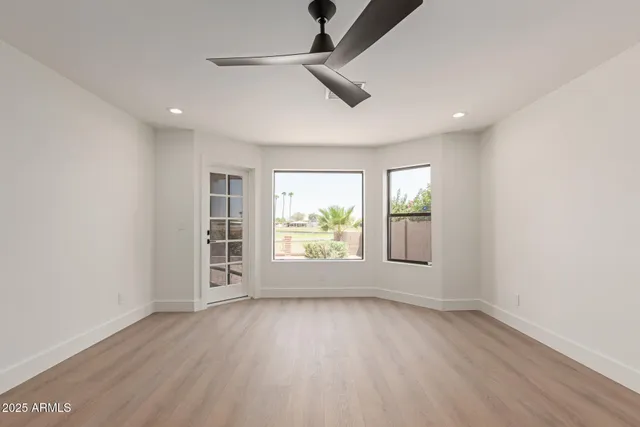 an empty room with wooden floor and windows