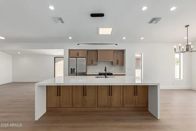 a large white kitchen with kitchen island a sink stainless steel appliances and cabinets