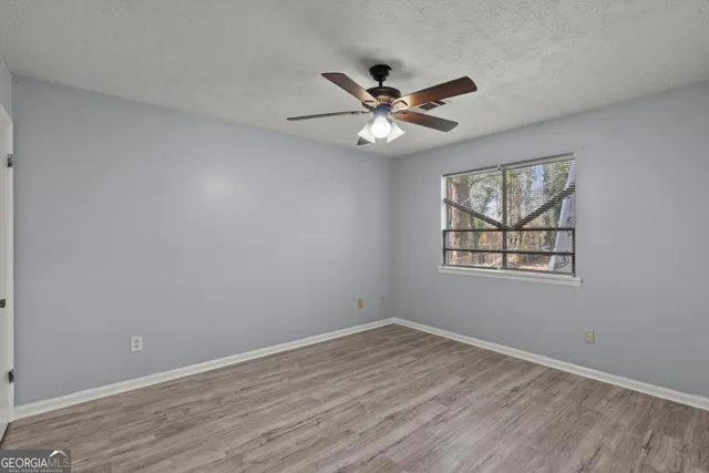 a view of empty room with wooden floor and fan