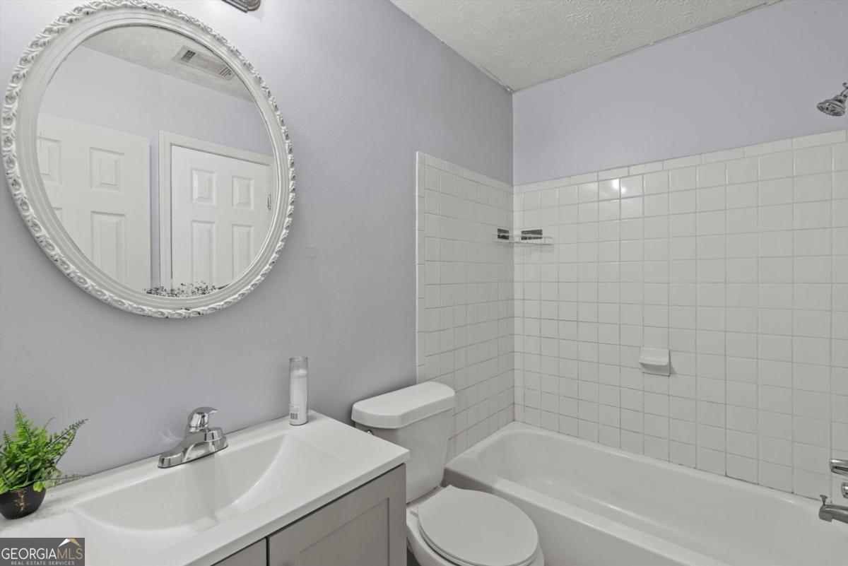 8877 Burnham Way Jonesboro, GA 30238 - Photo 19 of 23 a bathroom with a toilet a sink a mirror and bathtub