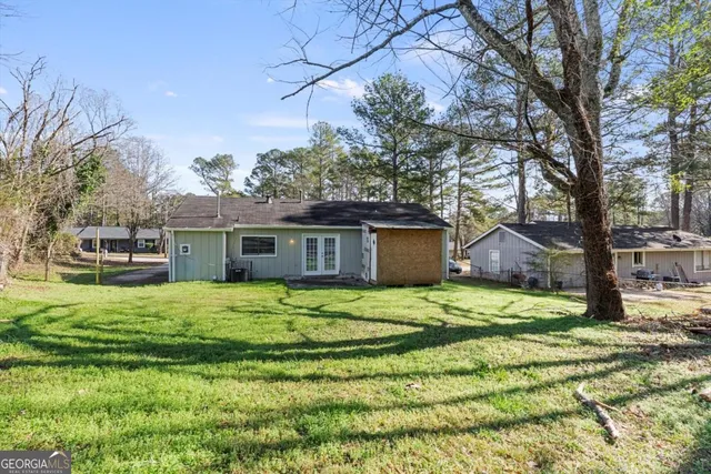 a house that has a big yard large trees with wooden fence