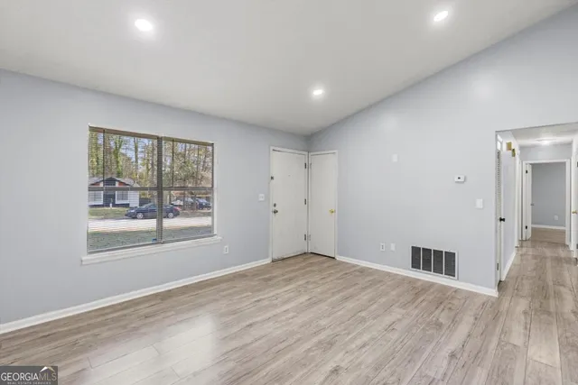 an empty room with wooden floor and windows