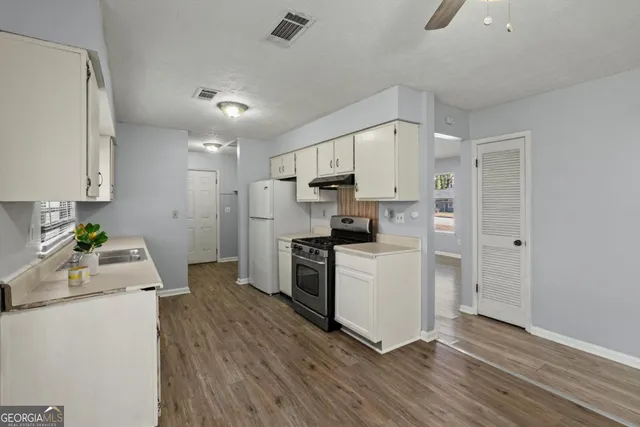 a kitchen with a refrigerator a stove top oven a sink and dishwasher with wooden floor