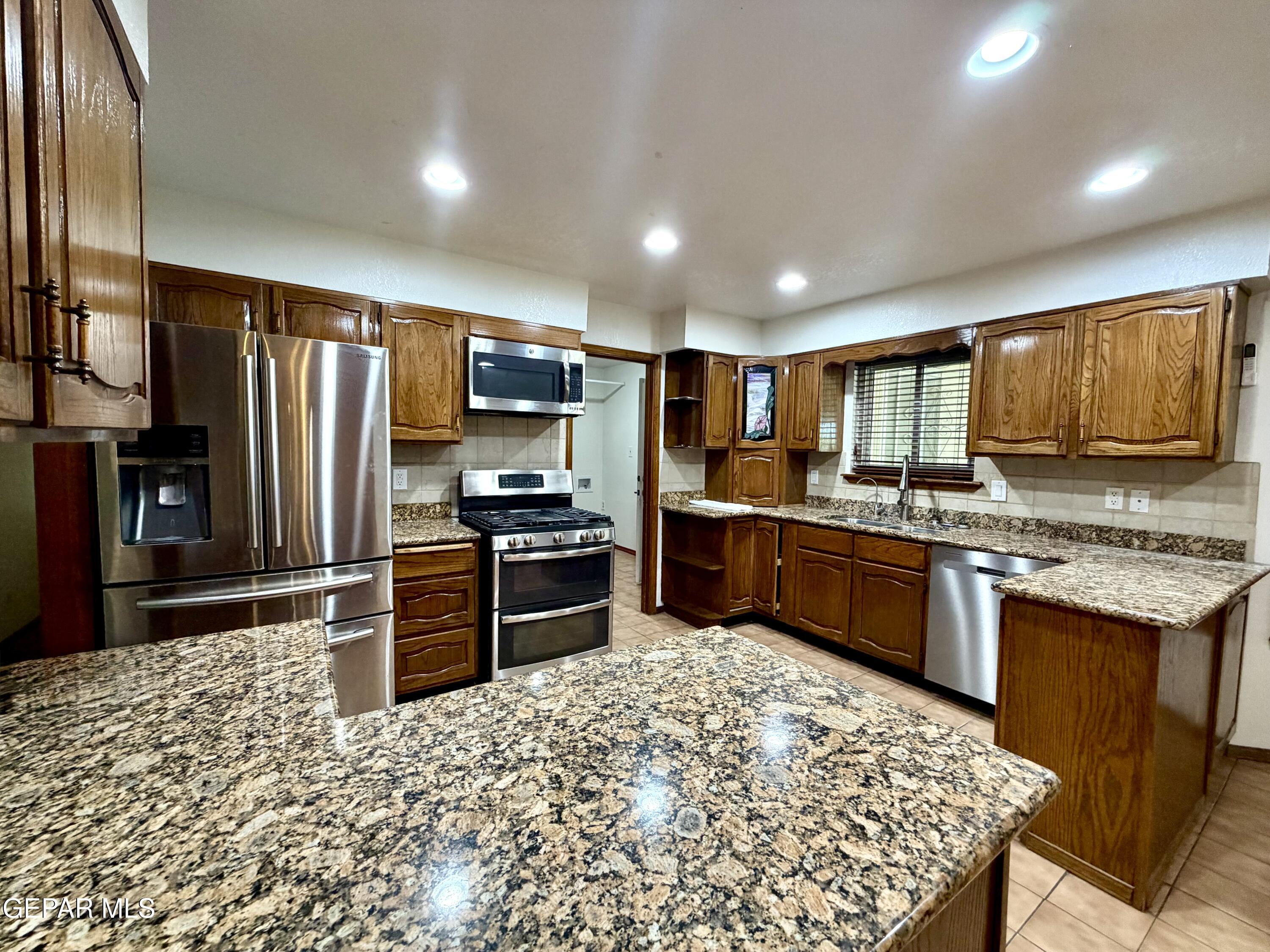 2452 West Ohara Road Anthony, NM 88021 - Photo 11 of 56 a kitchen with granite countertop stainless steel appliances and refrigerator