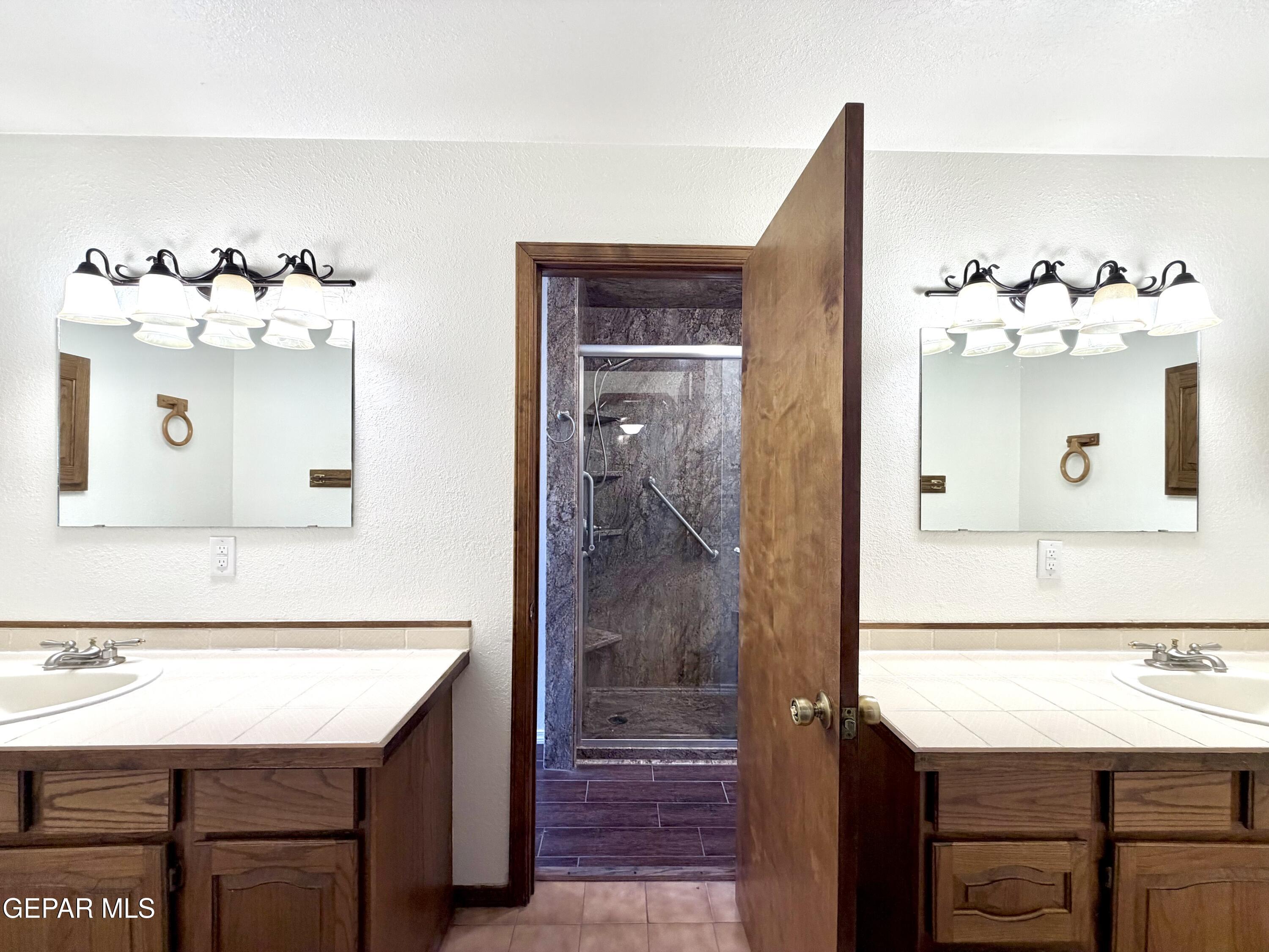 2452 West Ohara Road Anthony, NM 88021 - Photo 16 of 56 a bathroom with a sink a mirror and a shower