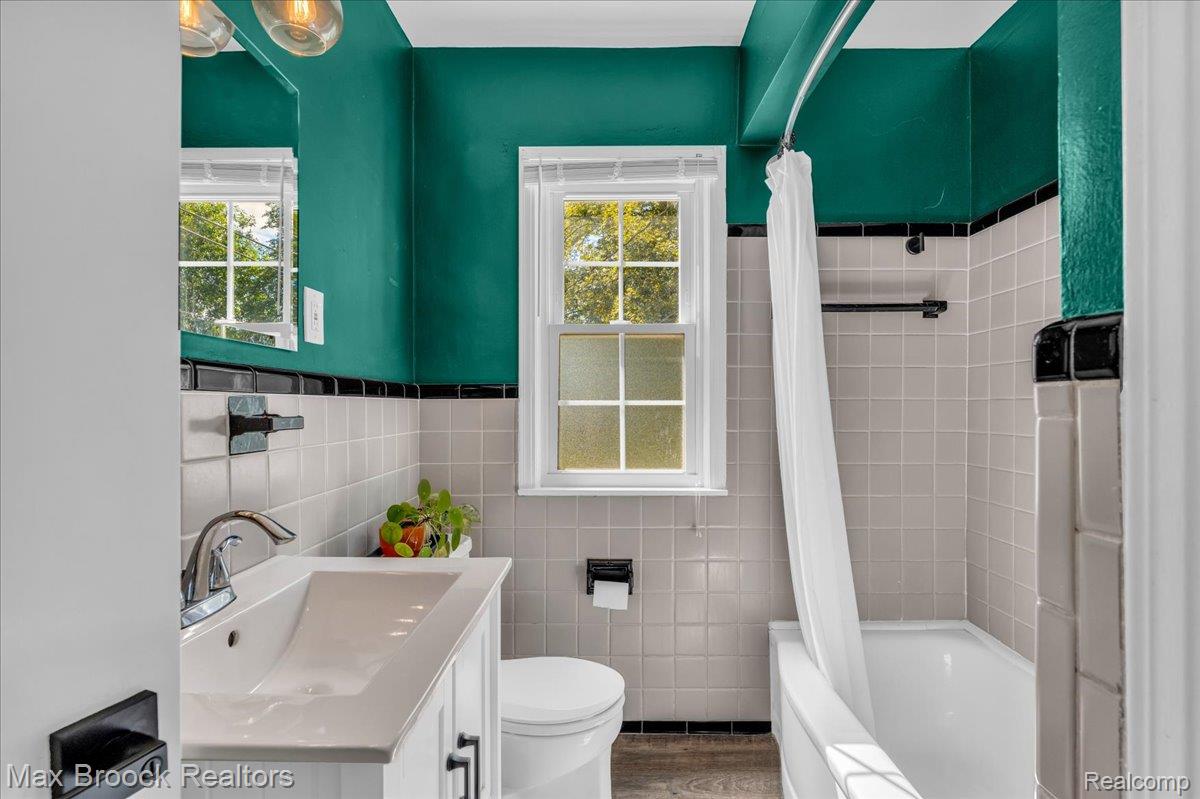 3711 Normandy Road Royal Oak, MI 48073 - Photo 16 of 40 Full bathroom with tile walls, shower / tub combo with curtain, vanity, and wainscoting