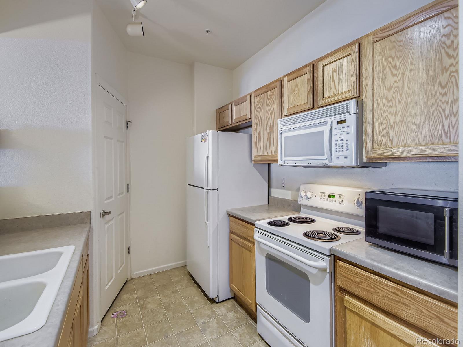 5255 Memphis Street, Unit 307 Denver, CO 80239 - Photo 23 of 29 a kitchen with stainless steel appliances a stove a microwave and a refrigerator