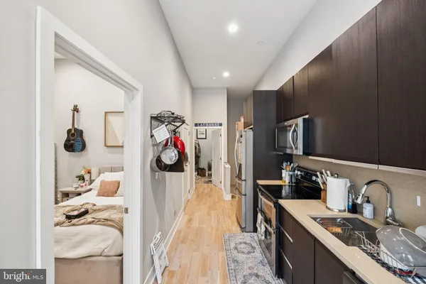 a kitchen with stainless steel appliances granite countertop a sink dishwasher stove and refrigerator with wooden floor