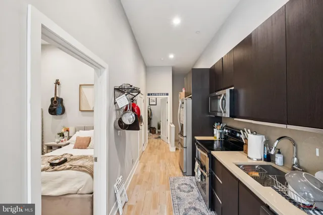 a kitchen with stainless steel appliances granite countertop a sink dishwasher stove and refrigerator with wooden floor