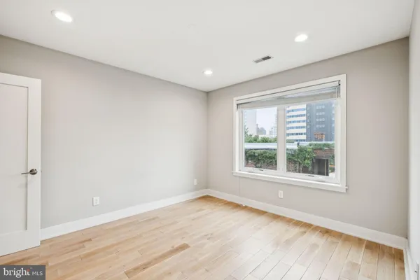 an empty room with wooden floor and windows