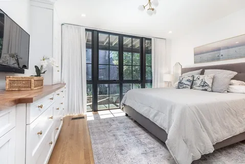 a bedroom with a large bed and a flat tv screen on dresser