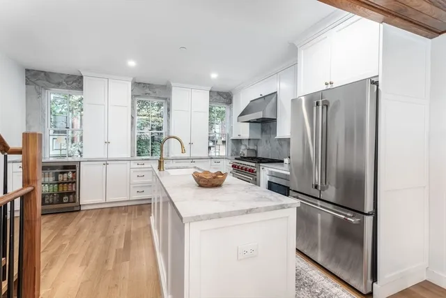 a kitchen with stainless steel appliances granite countertop a refrigerator a stove and a sink with wooden floor